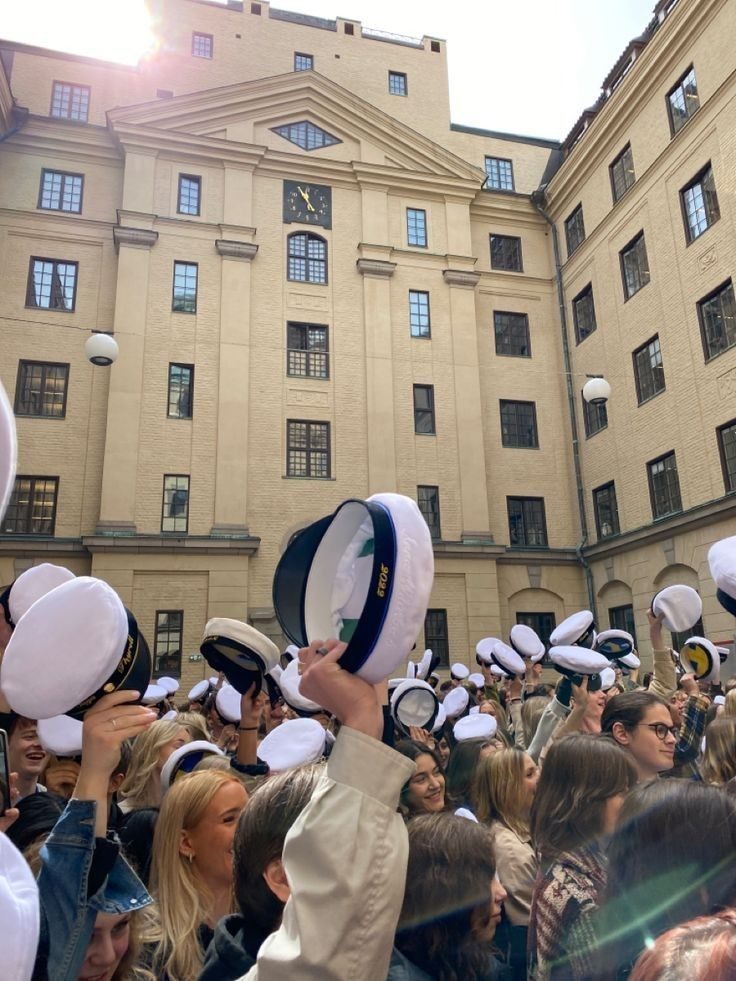 Studenter lyfter sina studentmössor på skolgården