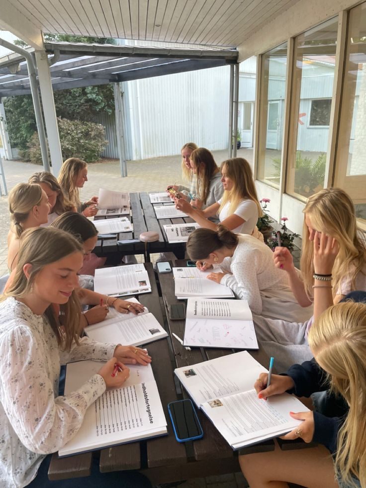 Elever arbetar tillsammans vid utomhusbord i skolans uteplats